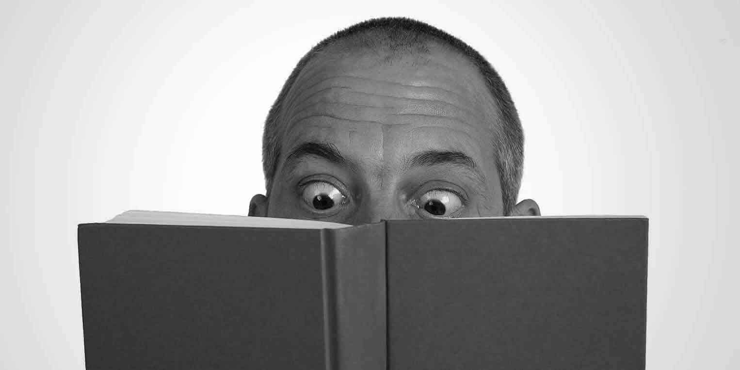 foto decorativa, homem arregalando olhos ao ler livro